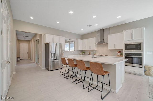 10251 Tiger Milkweed St, Las Vegas, NV 89141 - kitchen with appliances with stainless steel finishes, wall chimney exhaust hood, a breakfast bar area, light countertops, and white cabinets