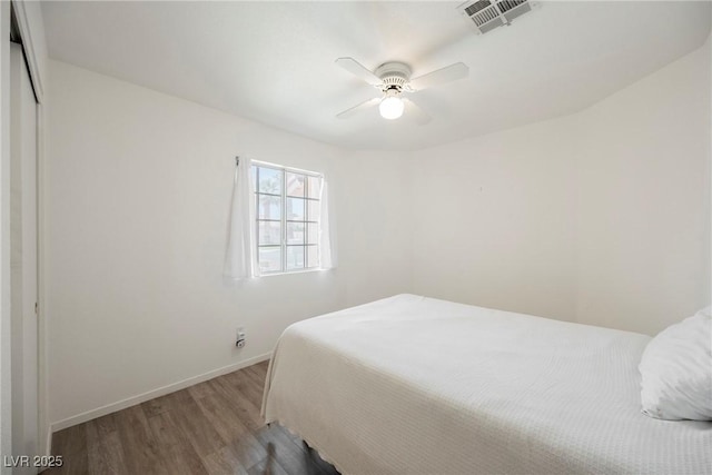 bedroom featuring visible vents, baseboards, ceiling fan, and wood finished floors