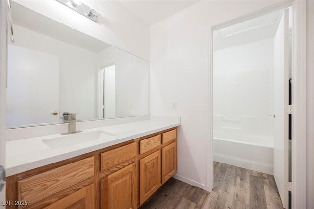 full bath featuring baseboards, wood finished floors, and vanity