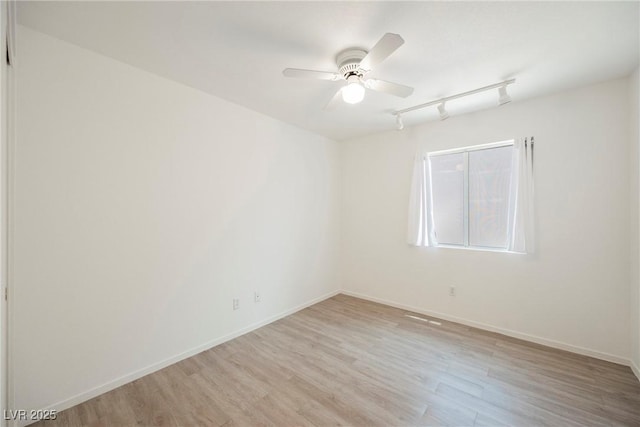 unfurnished room featuring rail lighting, ceiling fan, baseboards, and light wood finished floors