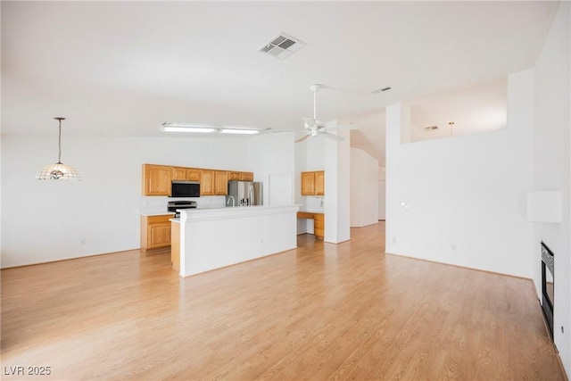 unfurnished living room with ceiling fan, visible vents, lofted ceiling, and light wood-type flooring