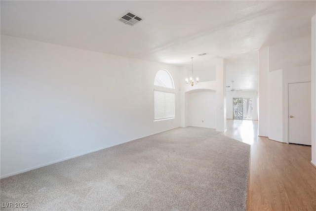 spare room with visible vents, plenty of natural light, a notable chandelier, and light colored carpet