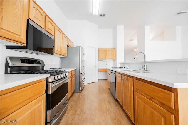 kitchen featuring visible vents, light countertops, a sink, light wood finished floors, and appliances with stainless steel finishes