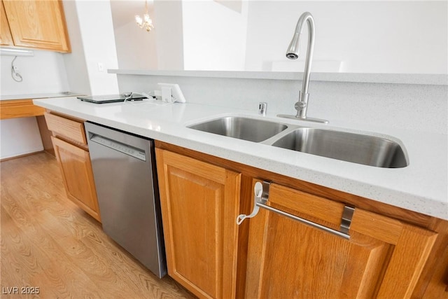 kitchen featuring stainless steel dishwasher, brown cabinets, a sink, and light wood-style flooring