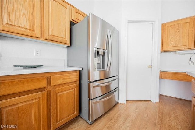 kitchen featuring stainless steel fridge, light countertops, and light wood-style floors