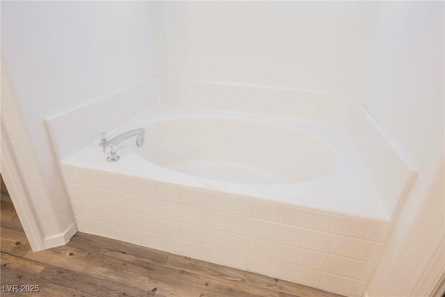 full bath with a garden tub and wood finished floors