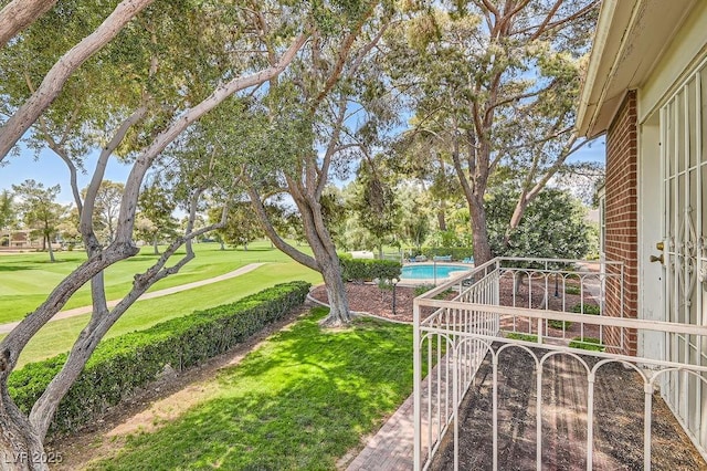 view of green lawn featuring an outdoor pool and view of golf course