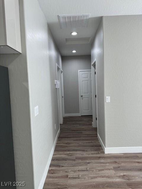 hallway featuring visible vents, recessed lighting, baseboards, and wood finished floors