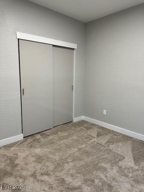 unfurnished bedroom with baseboards, carpet flooring, and a closet