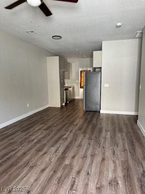 unfurnished living room with baseboards, a ceiling fan, and dark wood-style floors