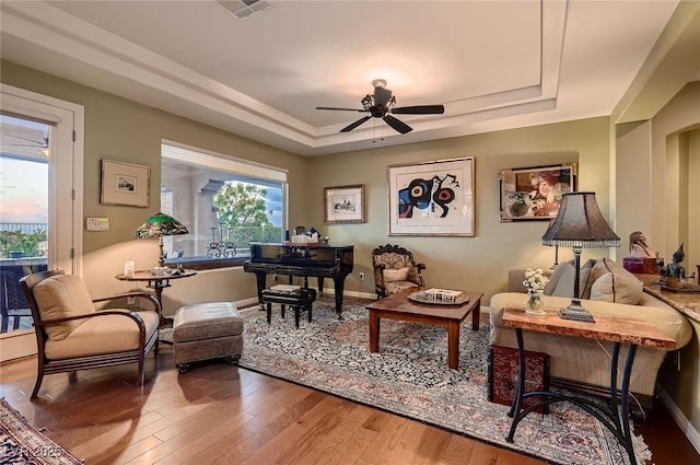 living area featuring visible vents, a raised ceiling, ceiling fan, and a healthy amount of sunlight