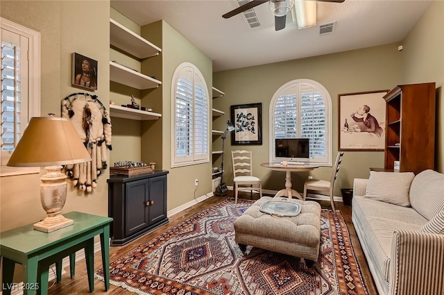 sitting room featuring a ceiling fan, visible vents, plenty of natural light, and wood finished floors