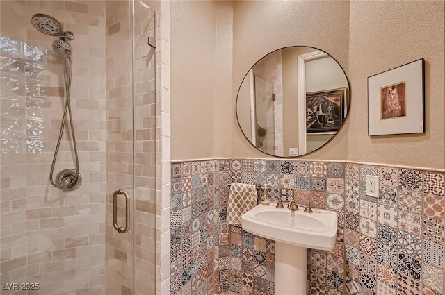 full bath featuring tile walls, a wainscoted wall, and a stall shower