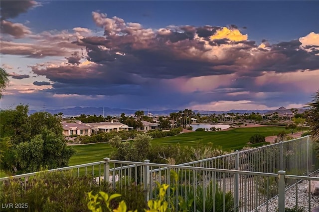 balcony at dusk with a water and mountain view and golf course view