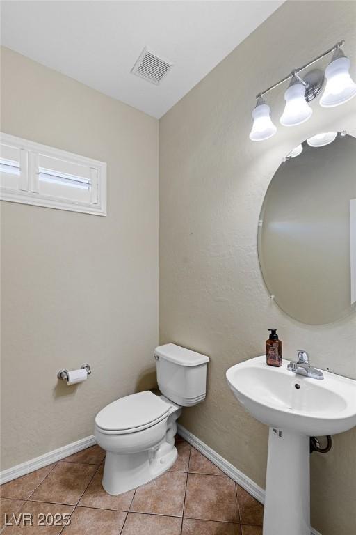 bathroom featuring a sink, toilet, tile patterned floors, baseboards, and visible vents