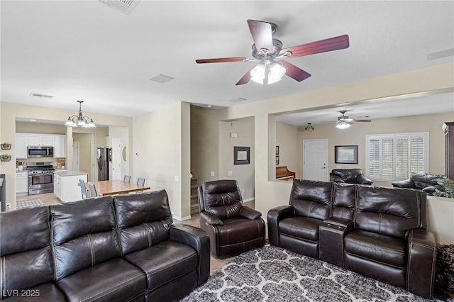 living area featuring ceiling fan with notable chandelier and visible vents