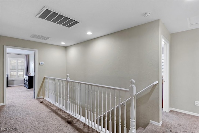corridor with an upstairs landing, carpet flooring, and visible vents