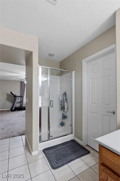 bathroom with tile patterned floors, a shower stall, baseboards, and vanity