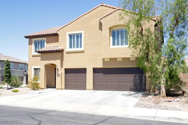 mediterranean / spanish-style home with a garage, stucco siding, a tile roof, and concrete driveway