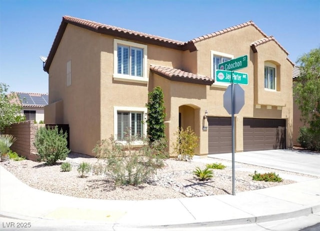 mediterranean / spanish house featuring a garage, stucco siding, driveway, and a tiled roof