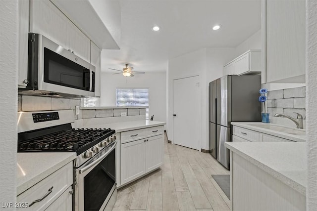 kitchen with tasteful backsplash, light countertops, stainless steel appliances, a ceiling fan, and light wood-type flooring