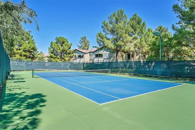 view of tennis court featuring community basketball court and fence