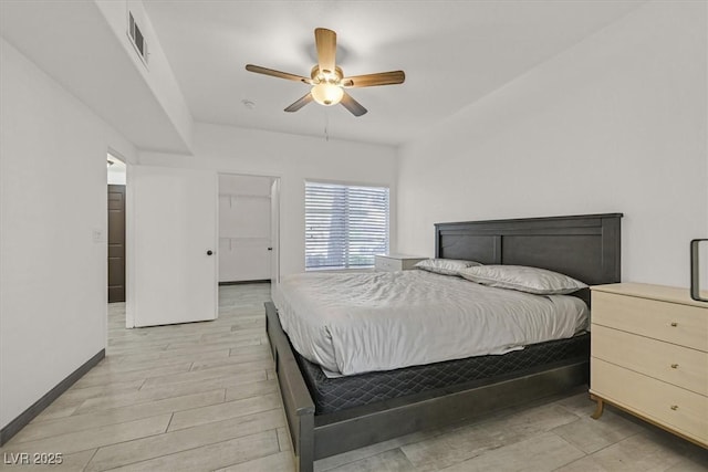 bedroom with visible vents, baseboards, a walk in closet, light wood-type flooring, and a ceiling fan