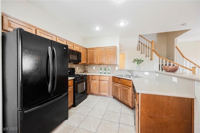 kitchen featuring a sink, a peninsula, decorative backsplash, light tile patterned floors, and black appliances