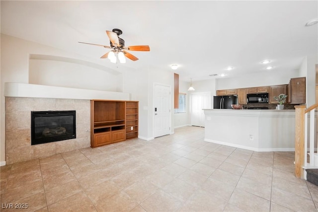 unfurnished living room featuring baseboards, ceiling fan, light tile patterned floors, and a fireplace