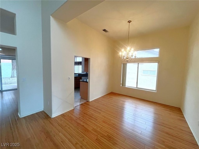 2925 Big Green Ln, Las Vegas, NV 89134 - empty room with a chandelier, healthy amount of natural light, light wood-type flooring, and a towering ceiling