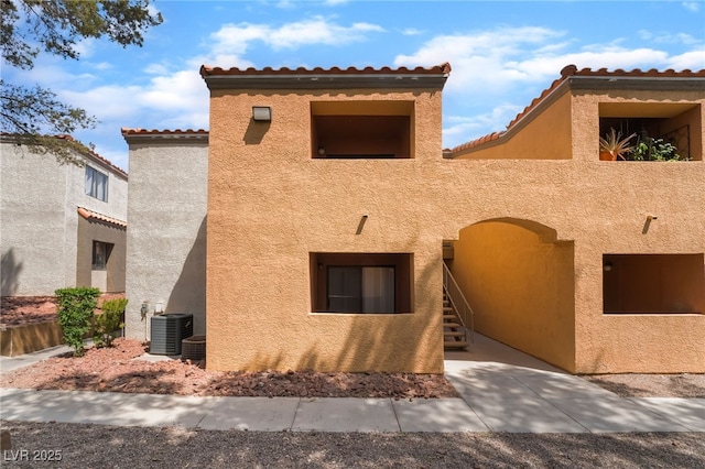 view of property exterior with a tiled roof, central AC unit, and stucco siding