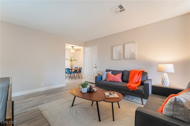 living area with baseboards, light wood-type flooring, and visible vents