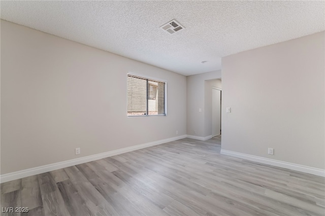 unfurnished room featuring baseboards, a textured ceiling, visible vents, and light wood-style flooring
