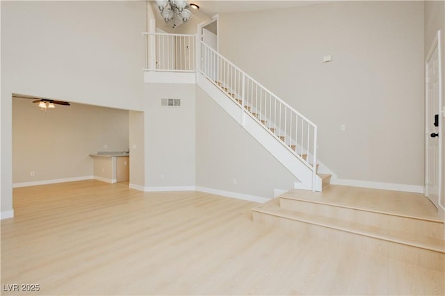 1617 Cave Spring Dr, Henderson, NV 89014 - unfurnished living room featuring visible vents, wood finished floors, stairway, an inviting chandelier, and a high ceiling