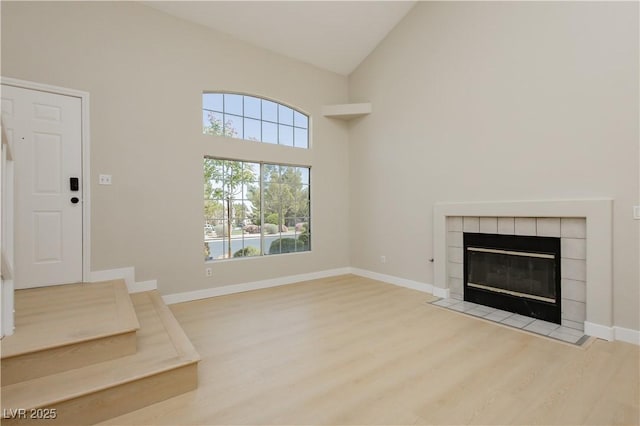 1617 Cave Spring Dr, Henderson, NV 89014 - unfurnished living room with high vaulted ceiling, baseboards, a fireplace, and light wood-style flooring
