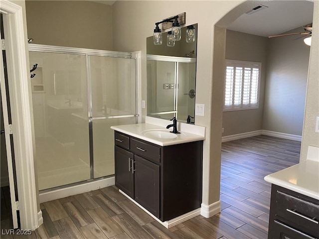 full bathroom featuring vanity, a ceiling fan, a shower stall, wood finished floors, and visible vents