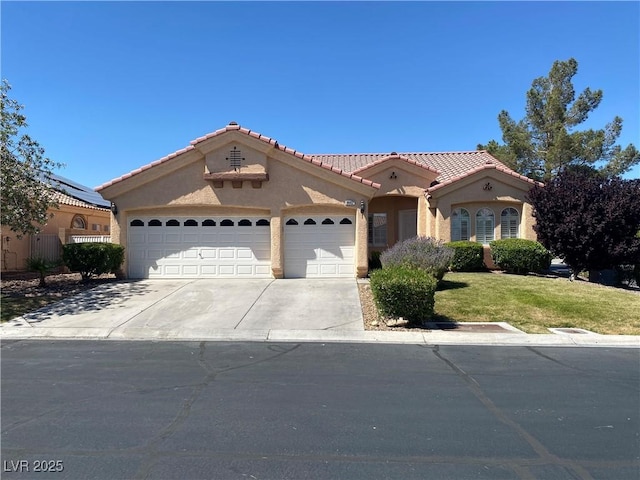mediterranean / spanish house with an attached garage, a tile roof, stucco siding, a front yard, and concrete driveway