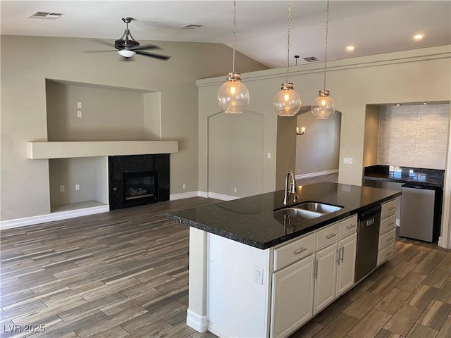 kitchen with a ceiling fan, stainless steel dishwasher, wood finished floors, a sink, and lofted ceiling