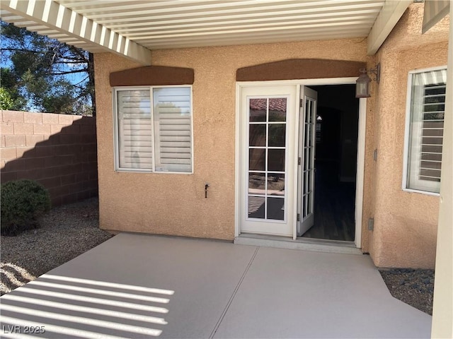 doorway to property with fence, a patio area, and stucco siding