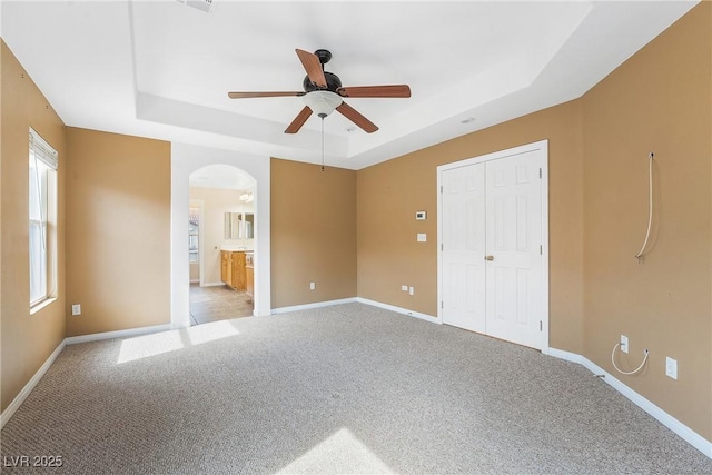 248 Hyssop Ct, Henderson, NV 89015 - unfurnished bedroom with a raised ceiling, baseboards, light carpet, and arched walkways