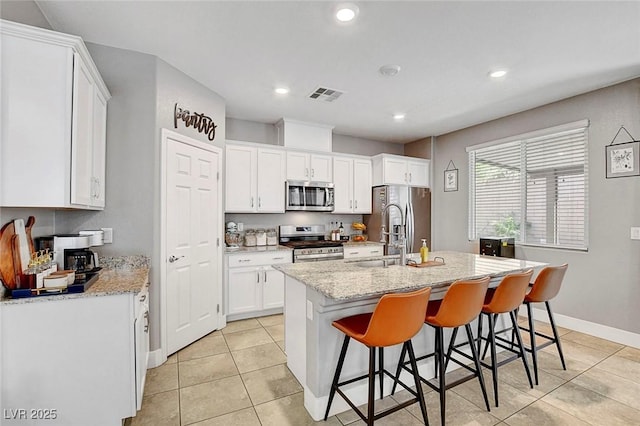kitchen with visible vents, appliances with stainless steel finishes, a sink, light tile patterned flooring, and an island with sink