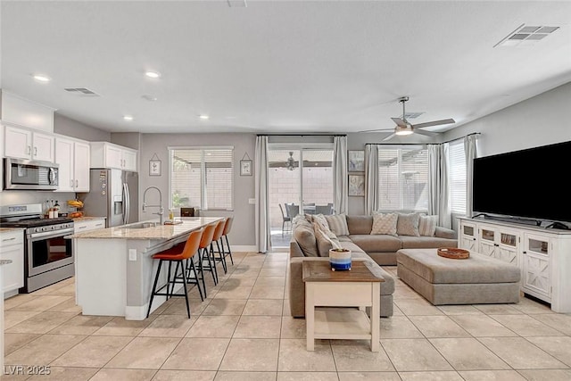 living area featuring ceiling fan, visible vents, and light tile patterned floors