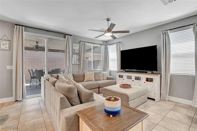 living area with a ceiling fan, baseboards, and light tile patterned flooring