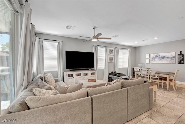 living area with light tile patterned floors, a healthy amount of sunlight, ceiling fan, and visible vents