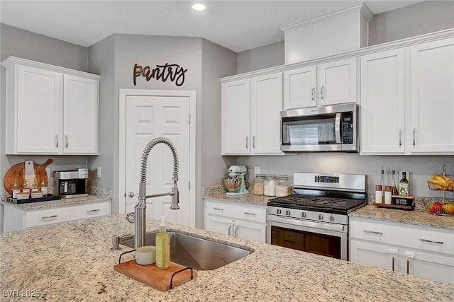 kitchen featuring light stone countertops, a sink, white cabinets, stainless steel appliances, and recessed lighting