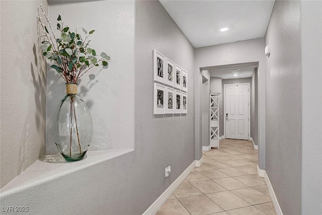 hall featuring baseboards and light tile patterned floors