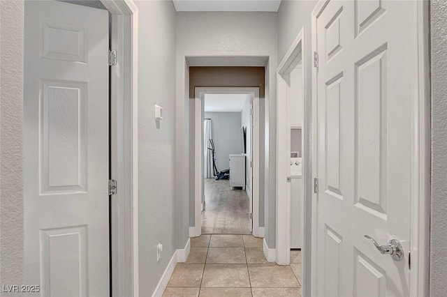 hallway with light tile patterned floors and baseboards
