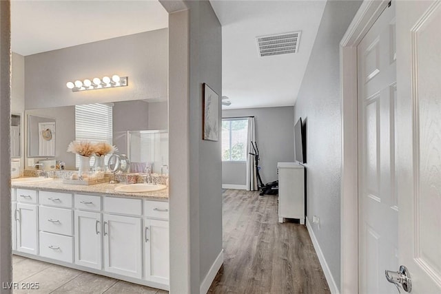 full bath with double vanity, visible vents, a shower stall, and a sink