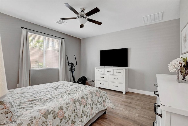 bedroom featuring baseboards, ceiling fan, wood finished floors, and visible vents