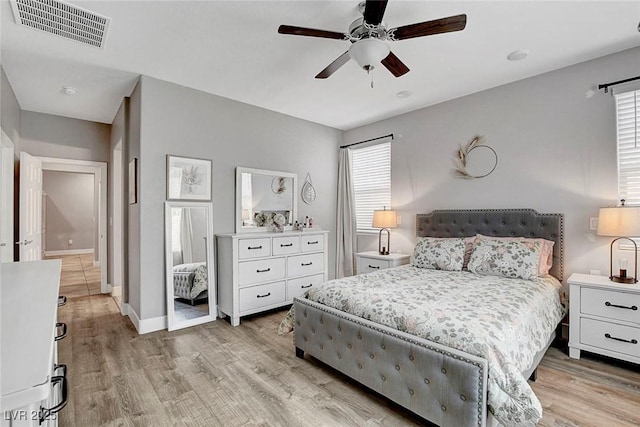 bedroom featuring baseboards, ceiling fan, light wood-style flooring, and visible vents
